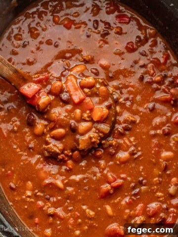 Cooked ladleful of turkey chili in black crockpot.