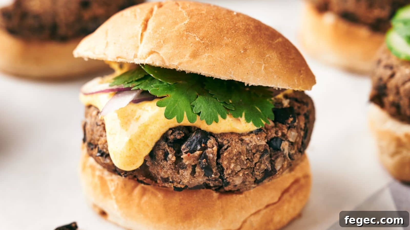 A black bean burger with a slice of cheese, cilantro, and red onion, served on a toasted bun.