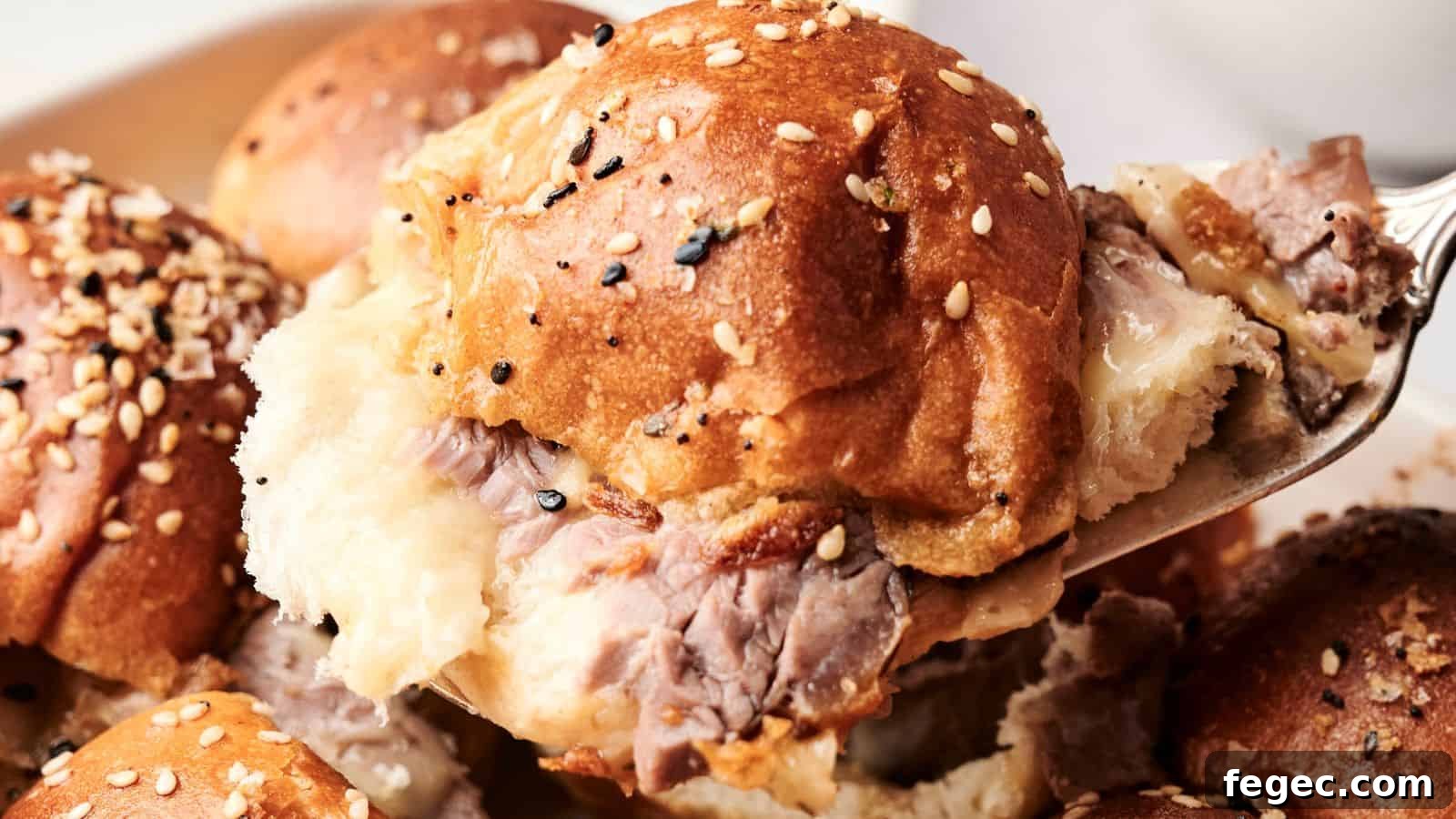 Close-up of a fork lifting a beef sandwich topped with sesame seeds on a soft bun, with more sandwiches in the background.