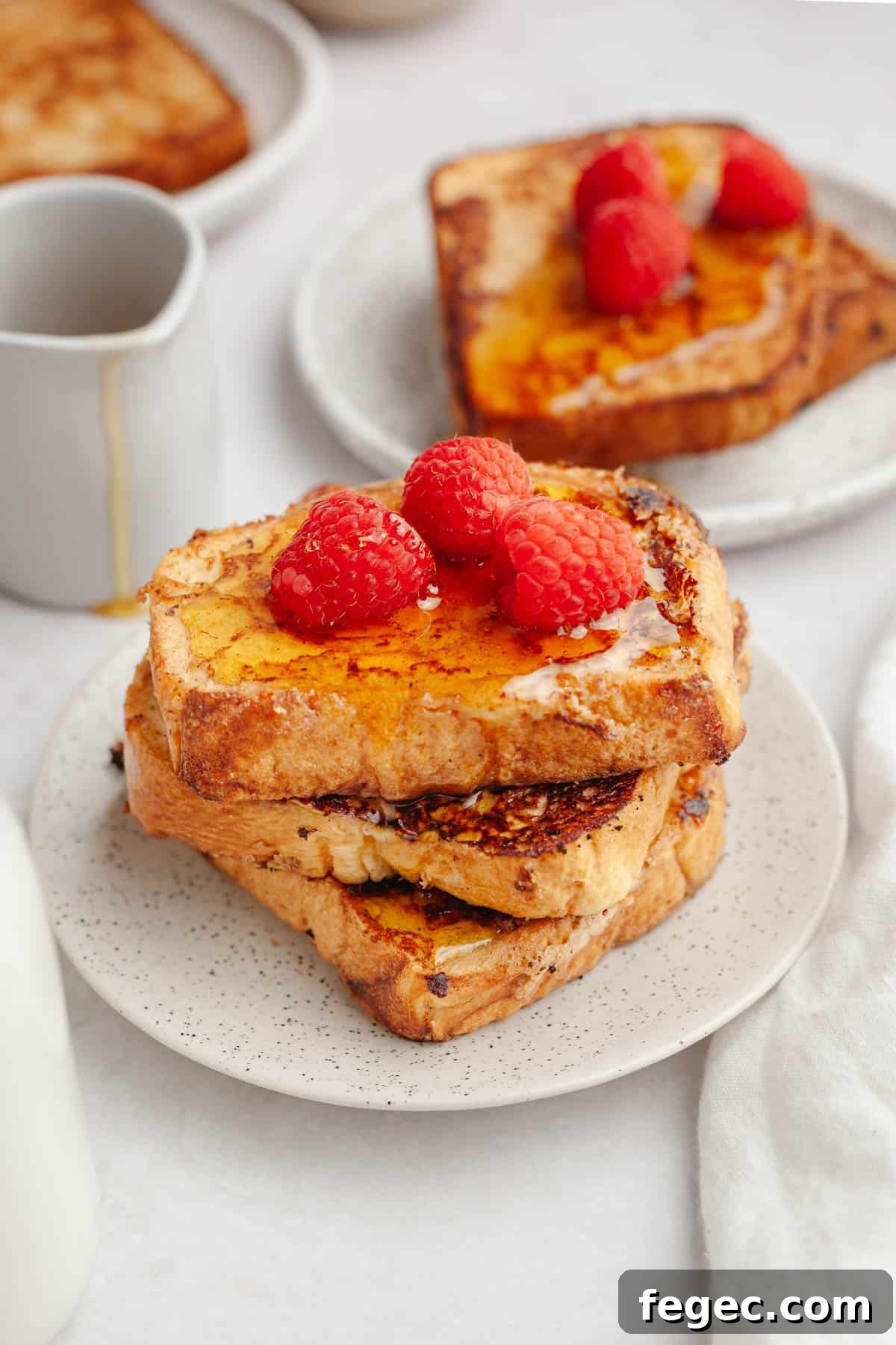 Three slices of homemade buttermilk french toast on a small plate, topped with raspberries.