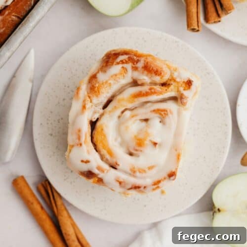A cinnamon roll with apple pie filling on a small plate.