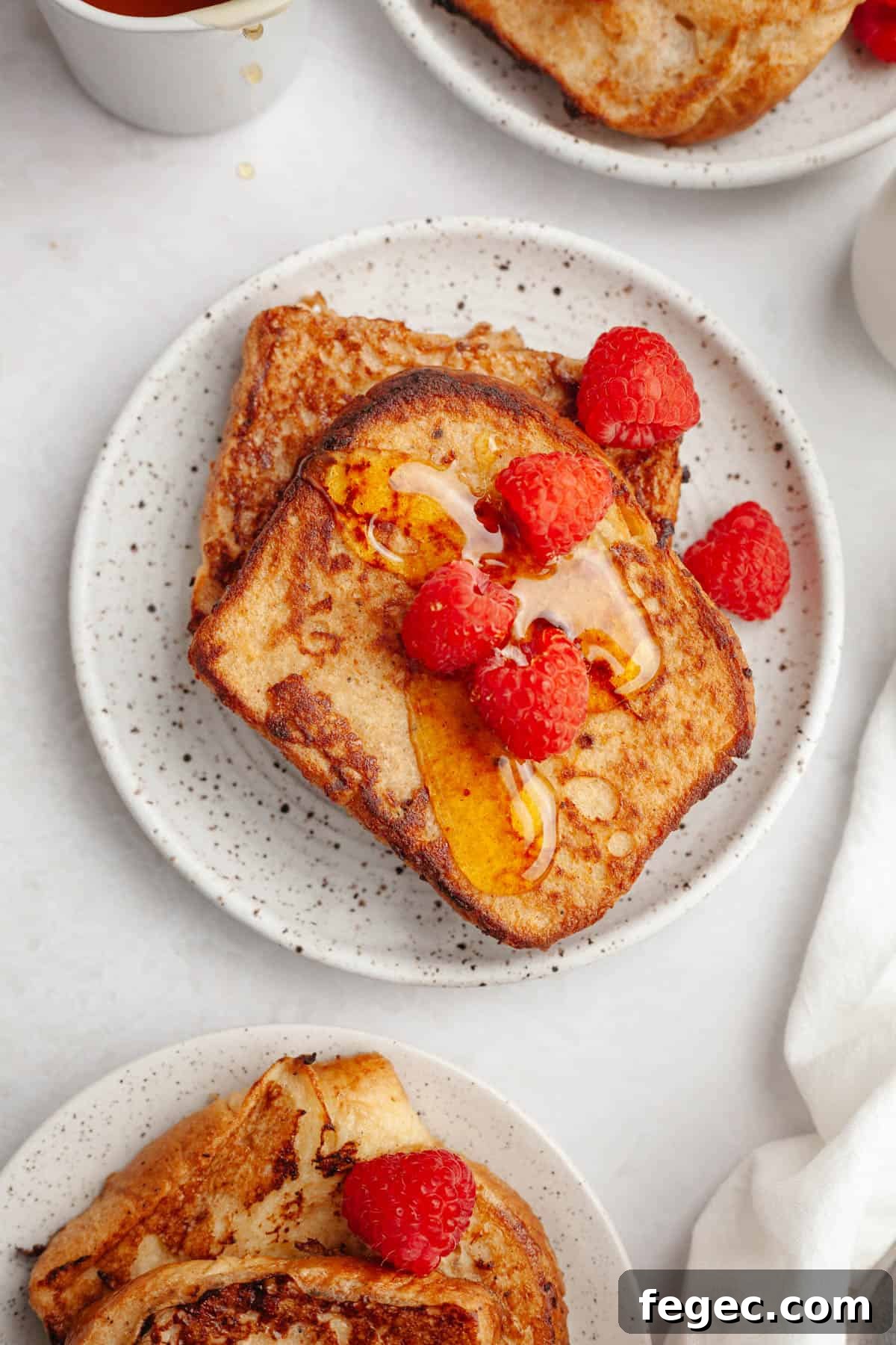 Two slices of homemade buttermilk french toast on a small plate, topped with raspberries.