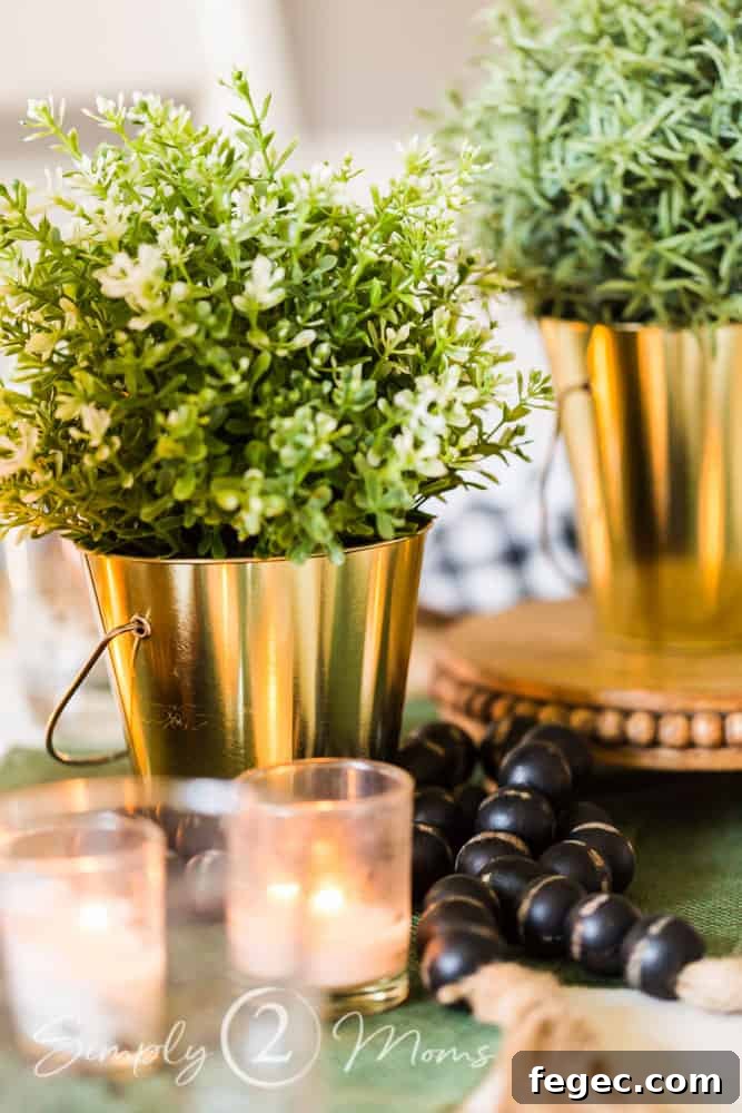 Spring Dining Room Ideas for Greenery Lovers 5 close up of small glass votive candle holders in front of bucket with faux plant and string of wood prayer beads laying next to them on table