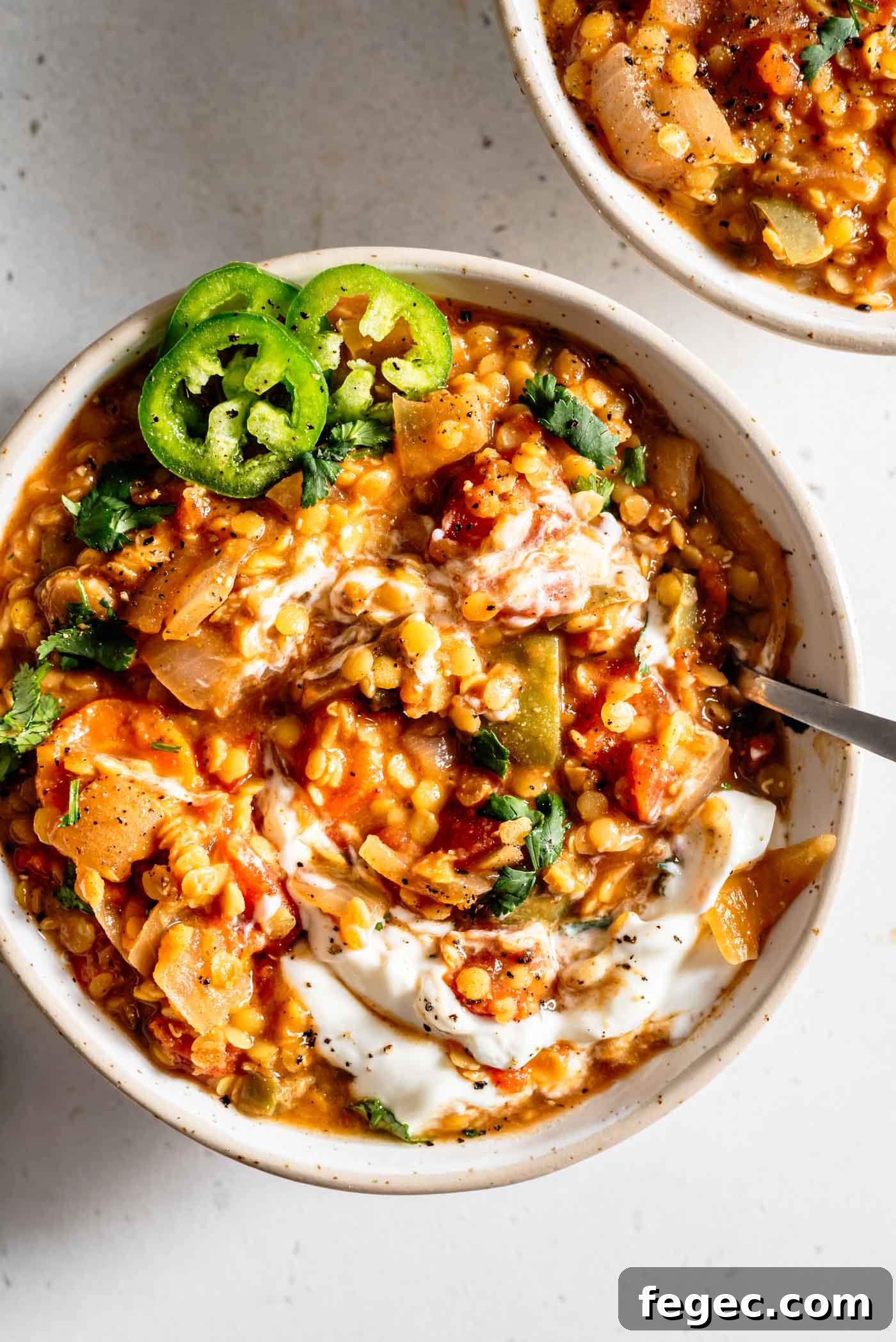 Bowl of lentil chili with sour cream and jalapeños on top.