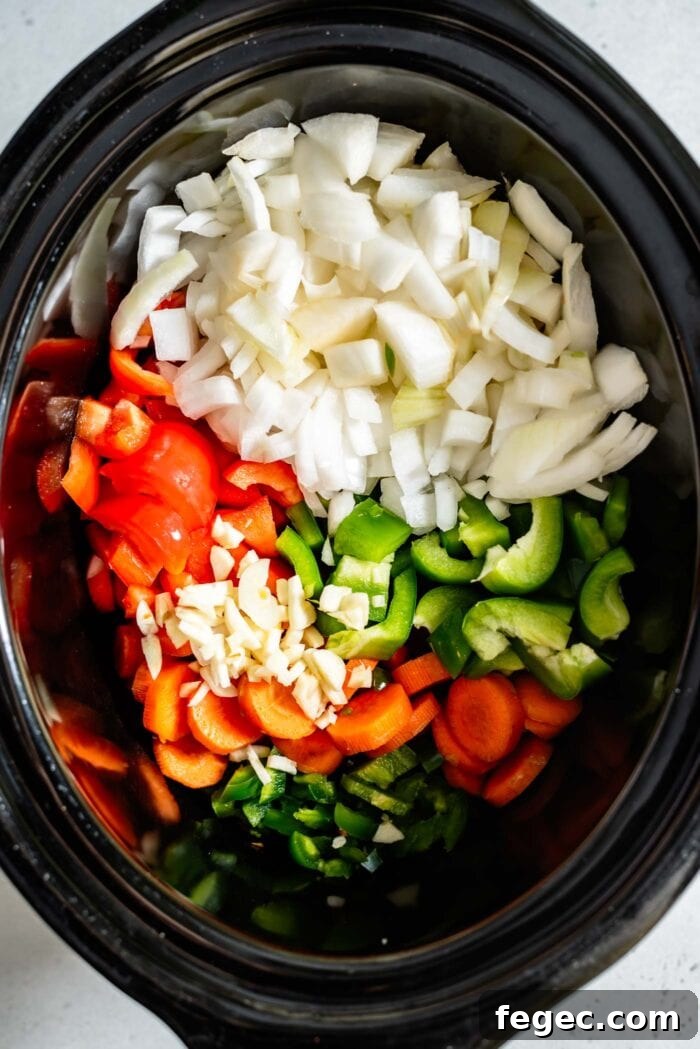 Chopped onion, bell peppers, carrot, jalapeno and garlic in a crockpot.