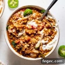 Overhead view of a bowl of lentil chili with sour cream and jalapeños on top.