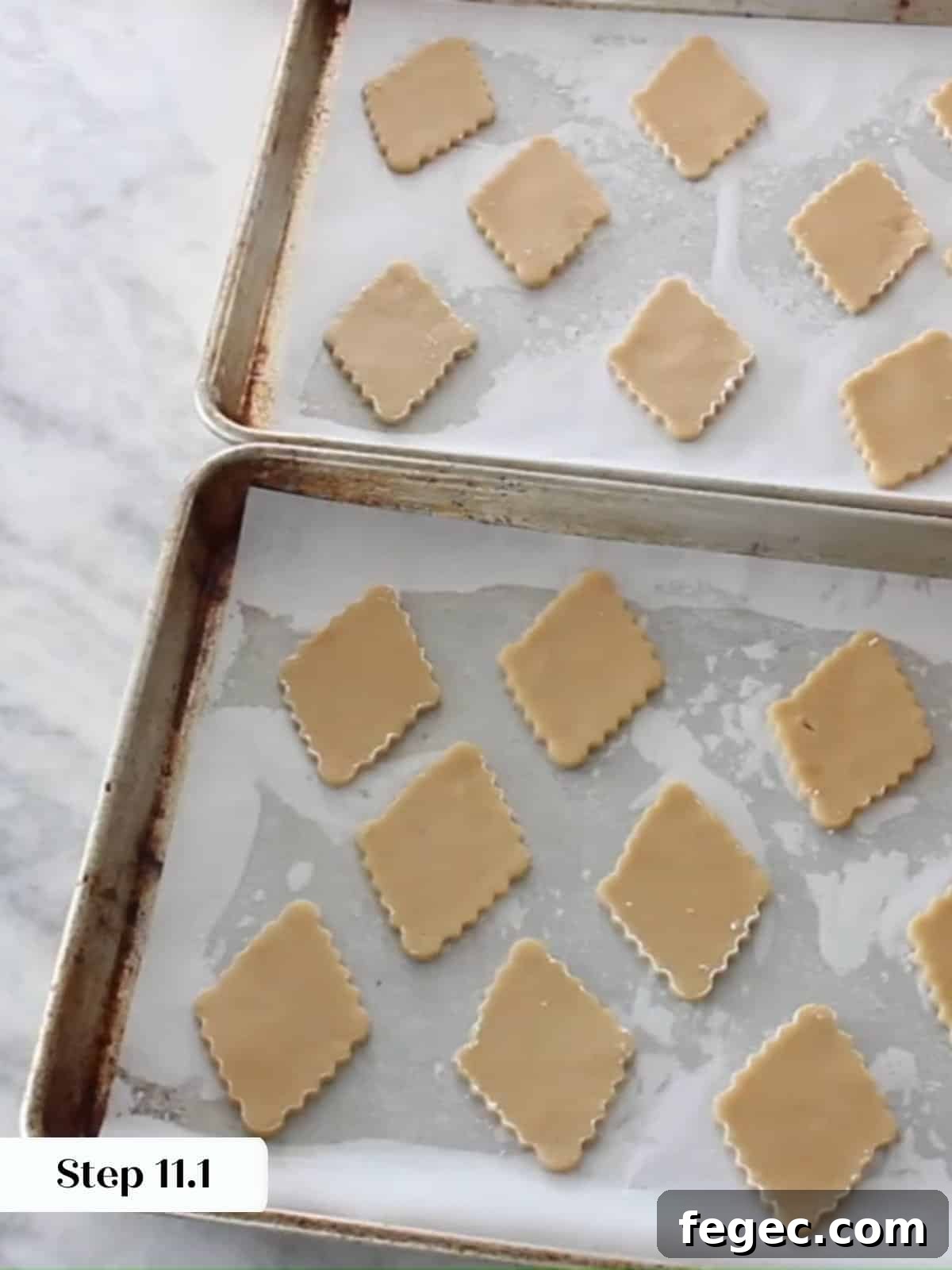 Unbaked Linzer cookie diamonds evenly spaced on a baking sheet lined with parchment paper.
