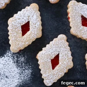 Raspberry Linzer Cookies on dark surface with extra powdered sugar.