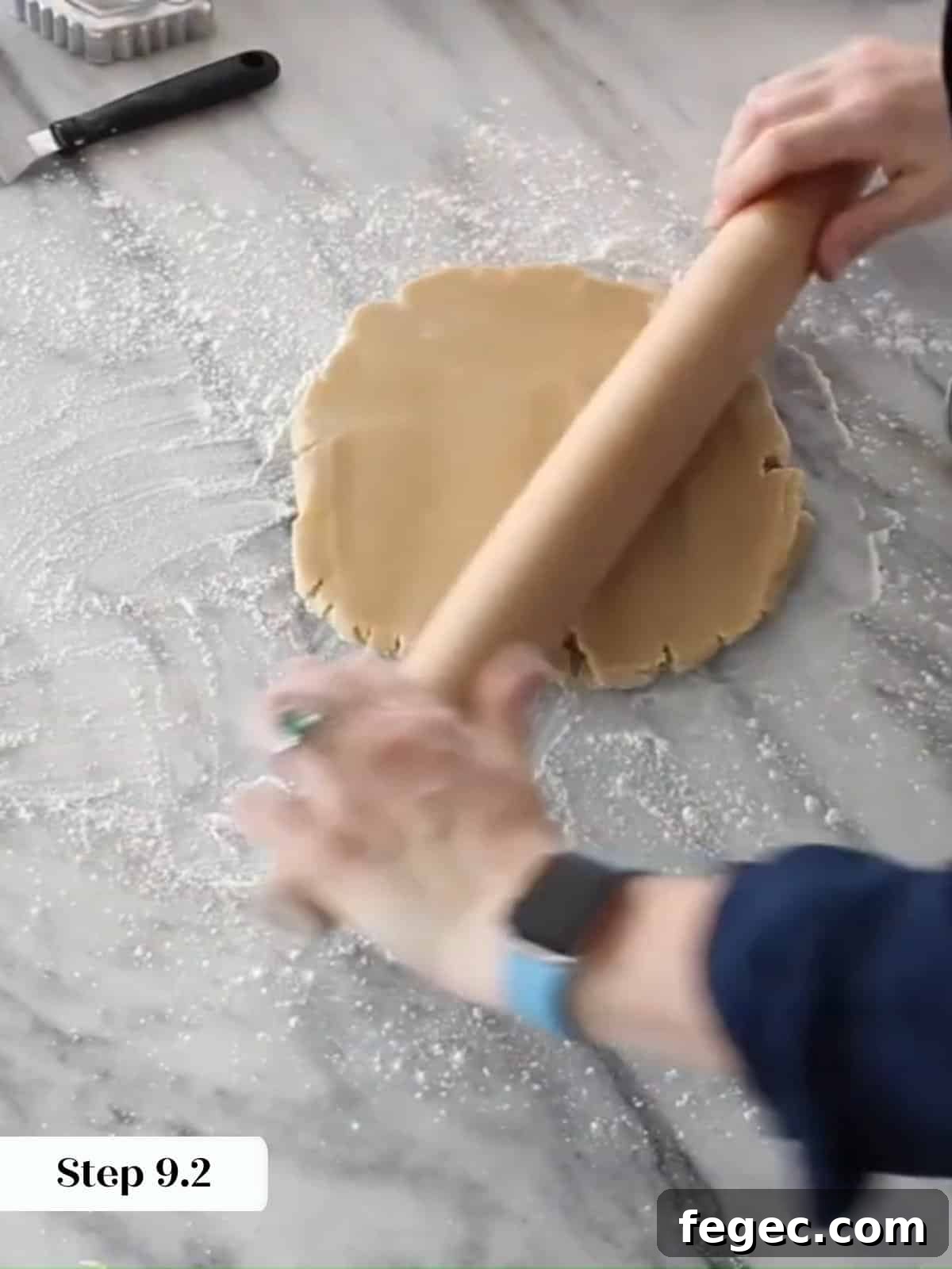 Cookie dough rolled thin with a wooden rolling pin on a lightly floured work surface.