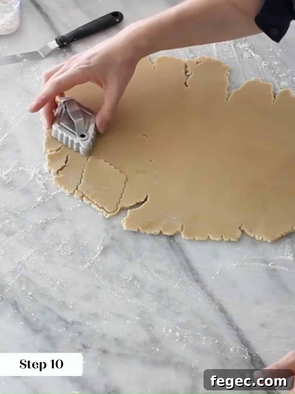 Freshly rolled Linzer dough being cut into even diamonds with a metal cookie cutter.