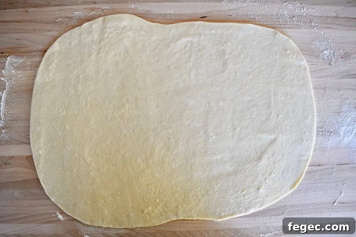 Small batch pizza dough rolled into a rectangular shape on a wood cutting board.