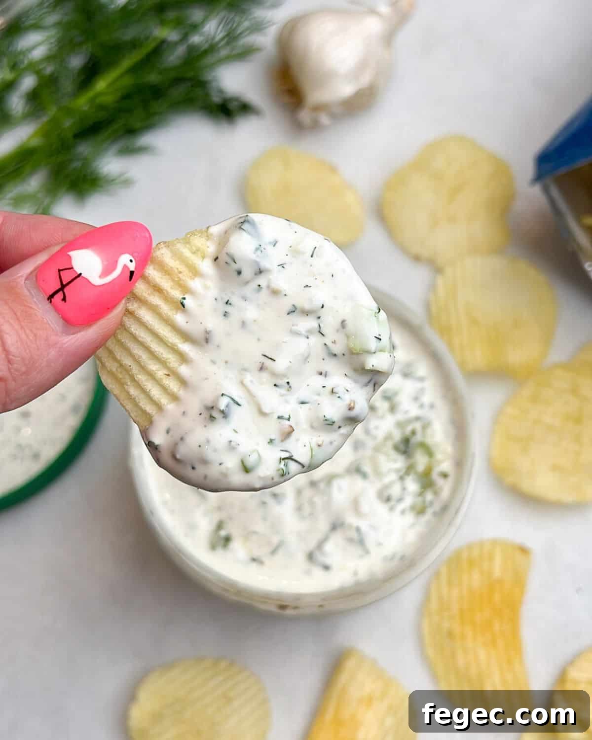 Creamy Dill Pickle Dip Recipe for Parties and Snacks 6 hand holding a chip dipped in ranch pickle dip