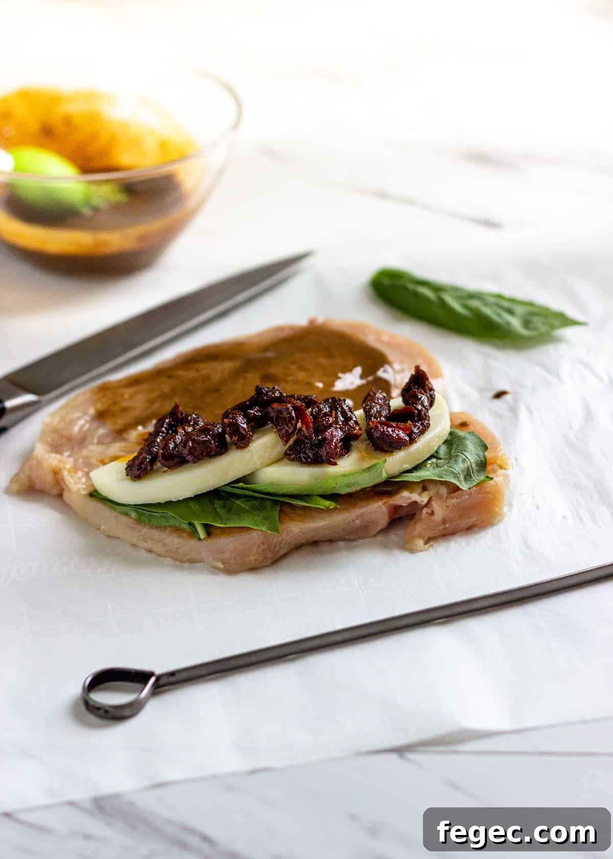 raw chicken split in half and filled with sun-dried tomatoes, mozzarella, and basil
