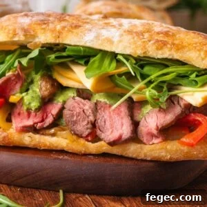 Steak Sandwich with sliced steak, melty cheese, arugula, grilled peppers, and savory sauce on fresh ciabatta bread.