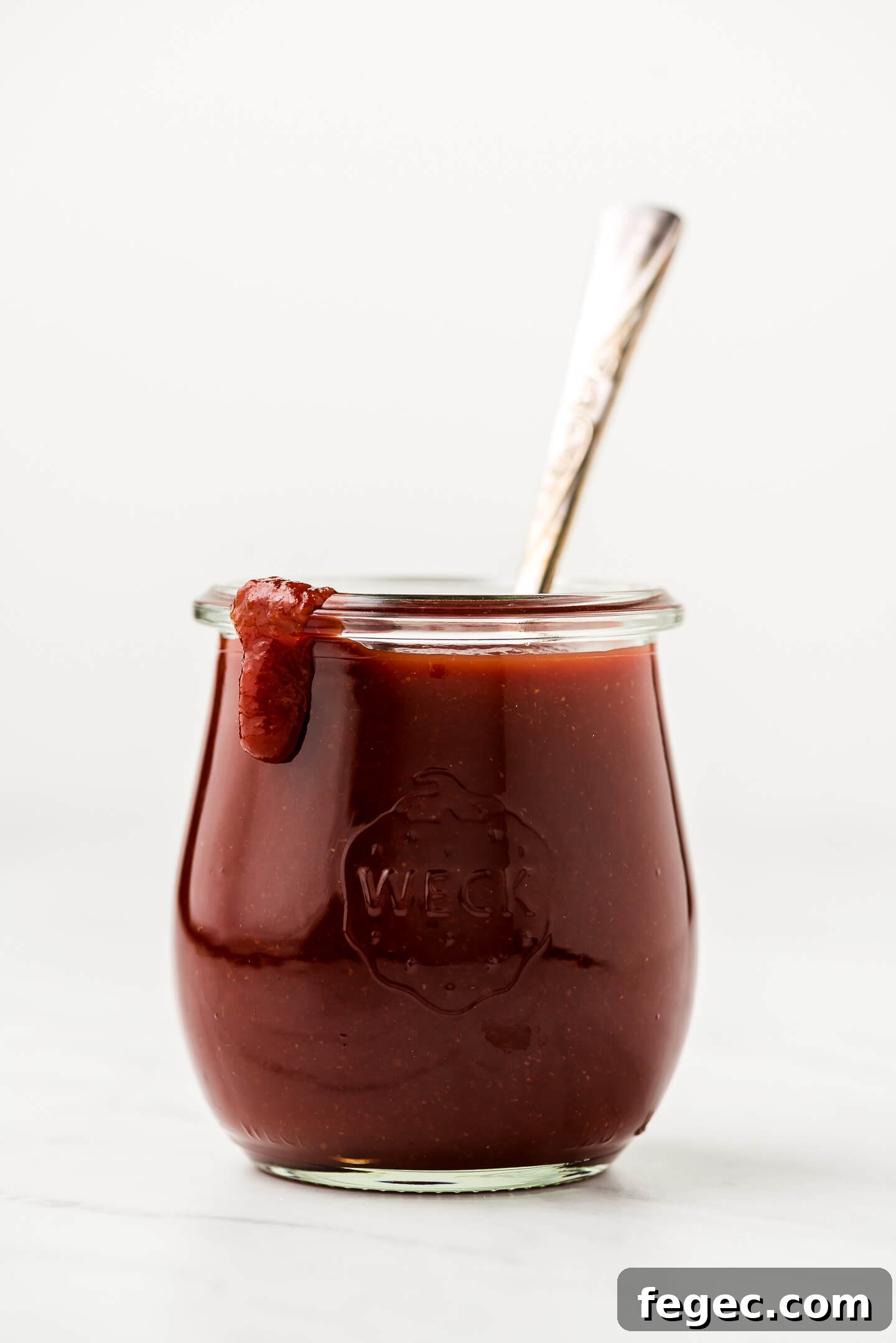 A jar of barbecue sauce with a drip of some down the side.
