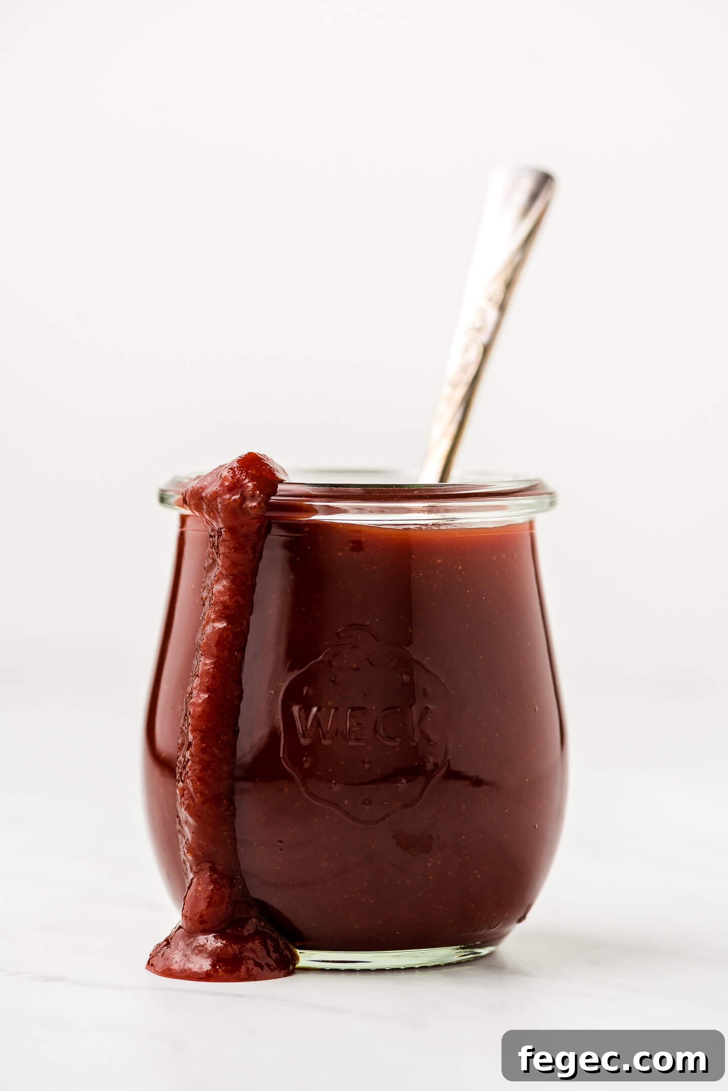 A jar of homemade barbecue sauce with some dripping down the side of the jar.