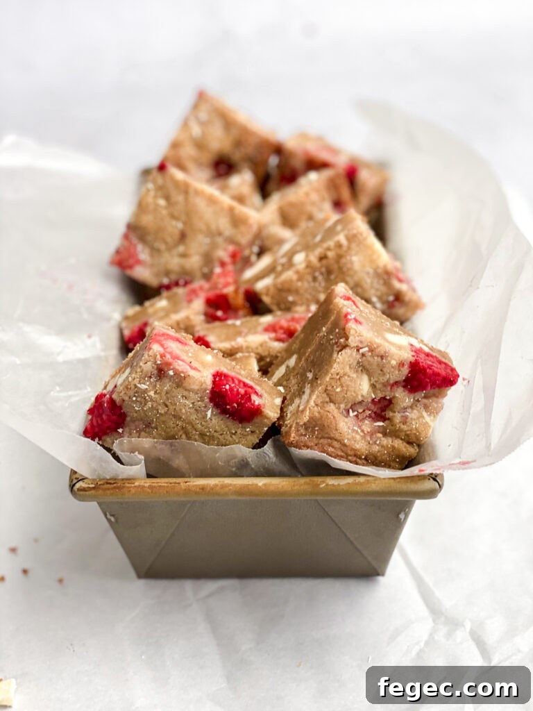 White Chocolate Raspberry Blondies Recipe — Chewy Fruity Bars 3 white chocolate raspberry blondies cut into squares and placed in a small loaf pan
