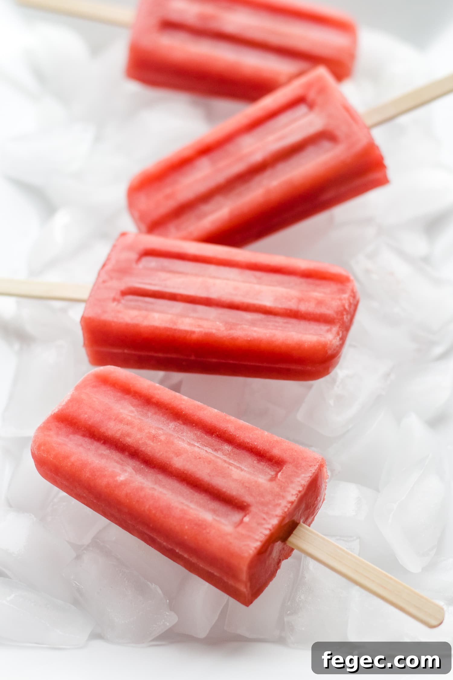 30 Fun Summer Staycation Ideas for Family and Friends 4 Four watermelon strawberry popsicles sitting on a bed of ice.