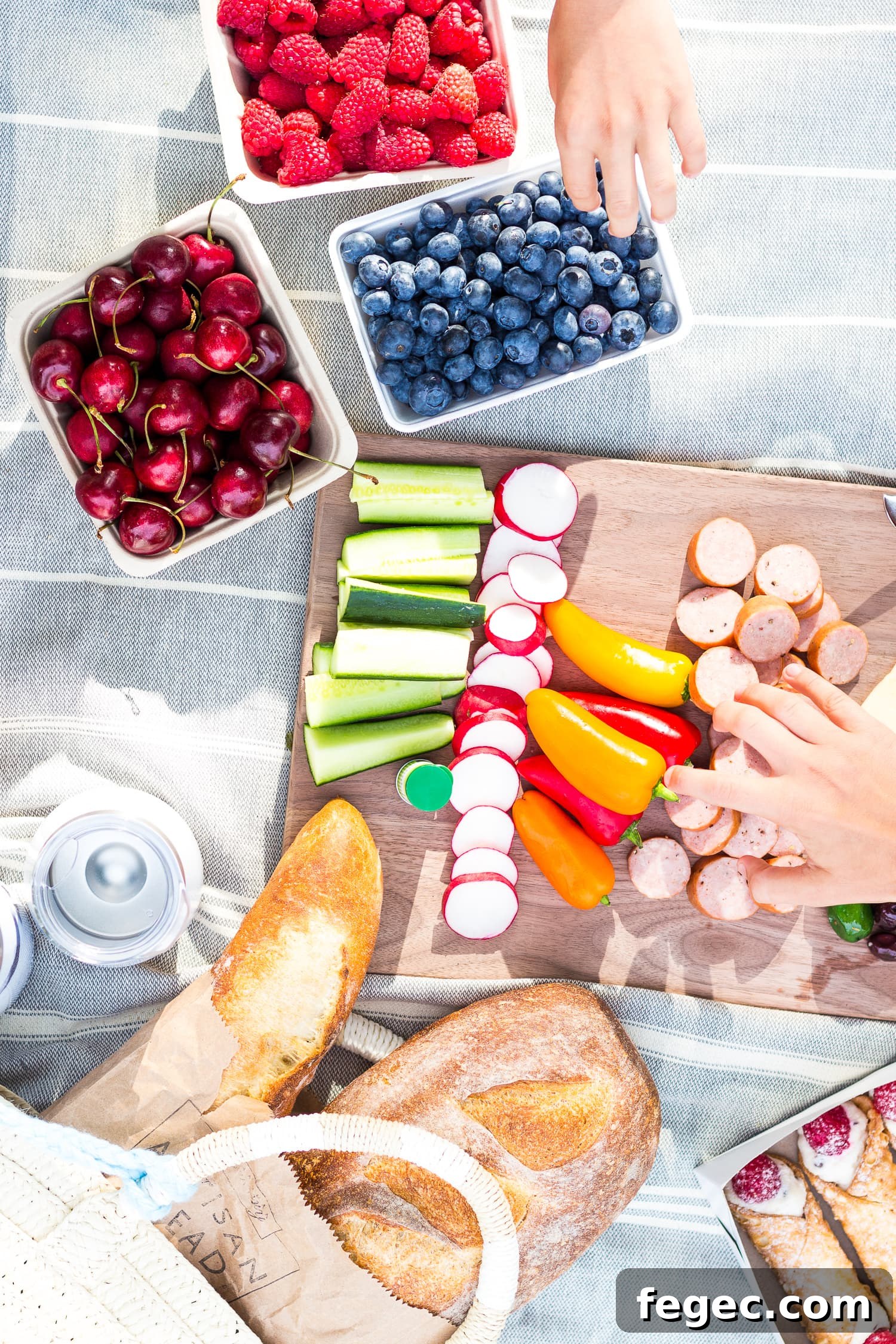 30 Fun Summer Staycation Ideas for Family and Friends 5 Overhead photo of a picnic set up on a blanket with two childrens hands reaching in.