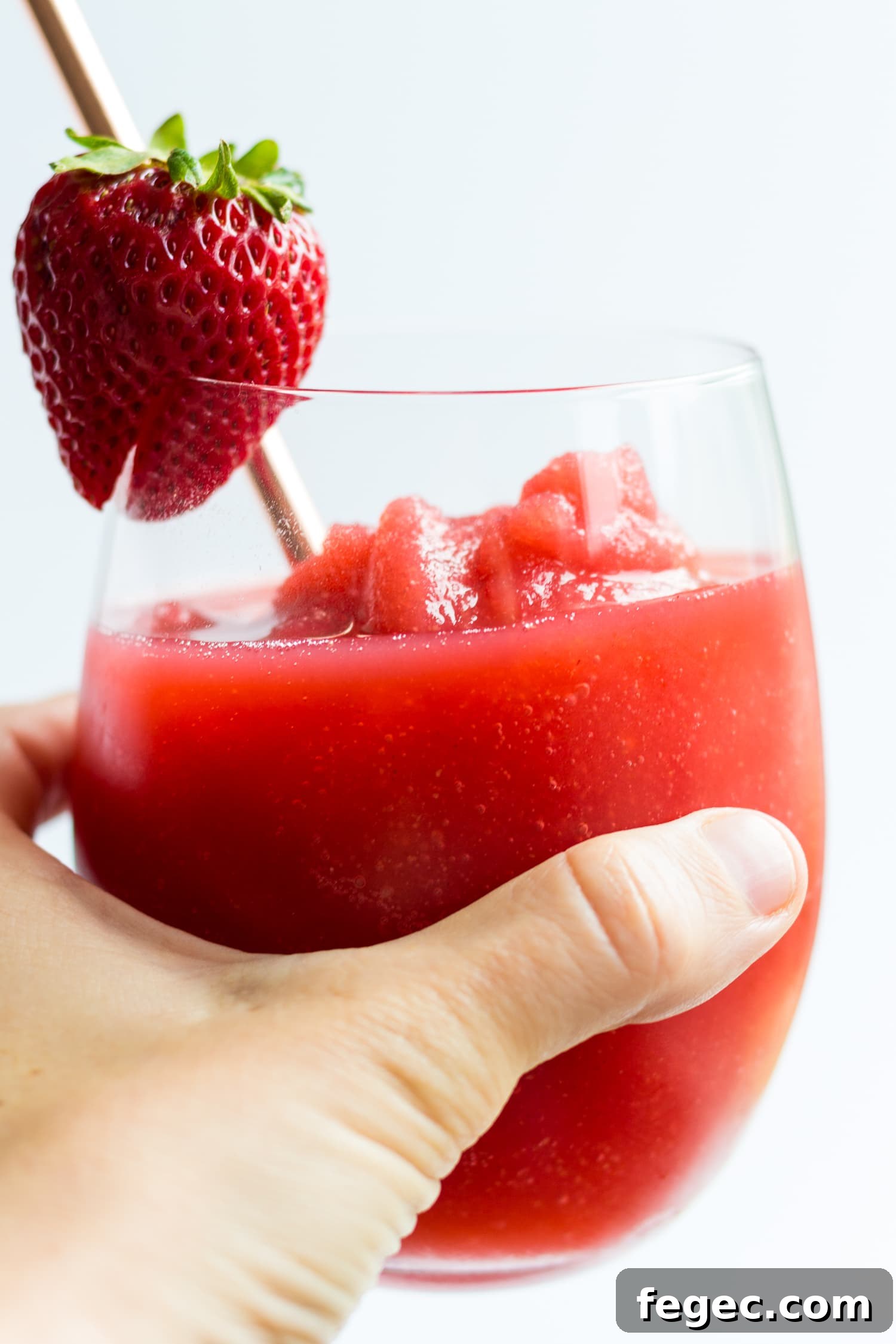 30 Fun Summer Staycation Ideas for Family and Friends 8 Hand holding glass of strawberry wine slushie.
