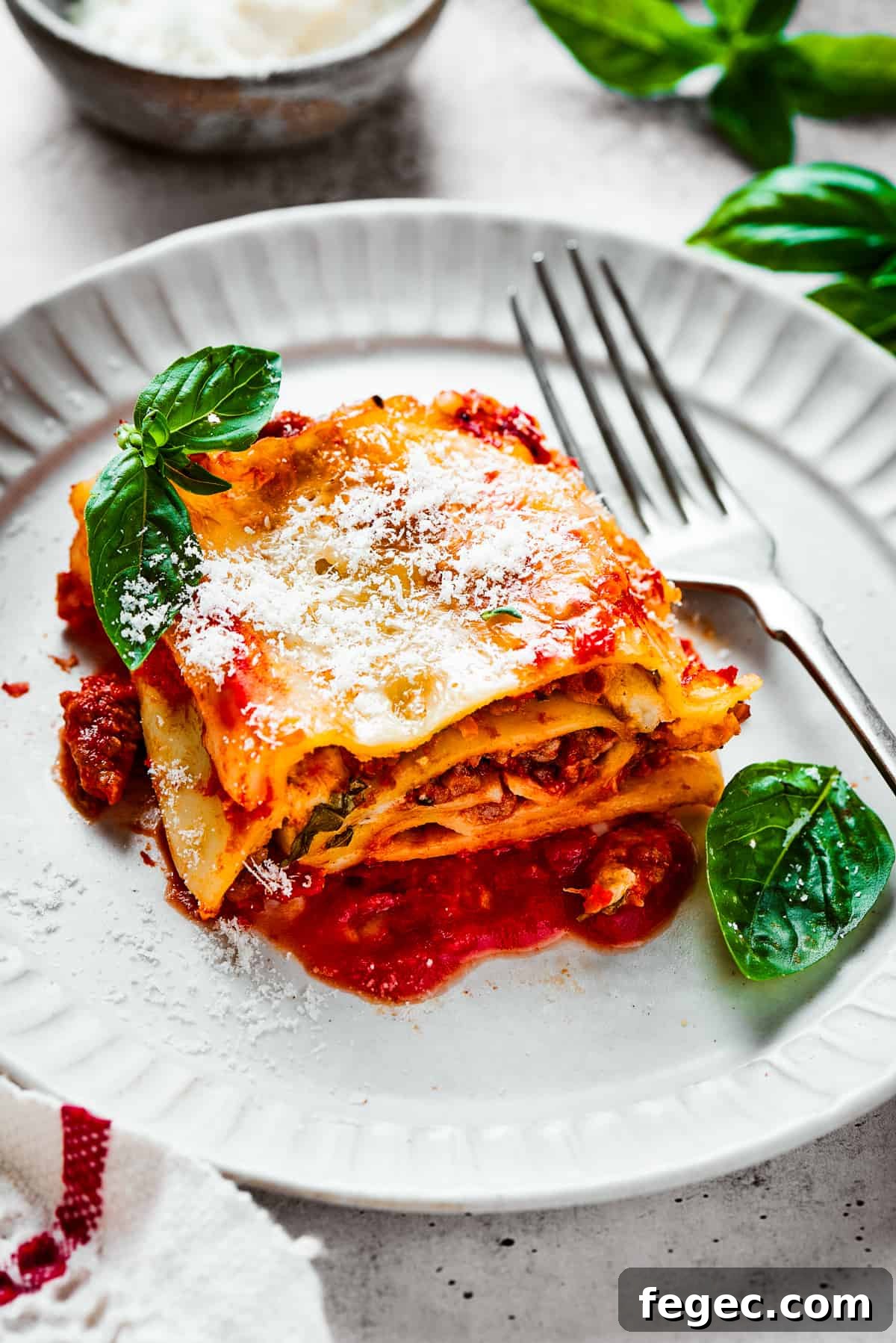 Cheesy Lasagna Roll-Ups Recipe for Family Dinners 2 A lasagna roll on a plate with basil leaves and a fork.