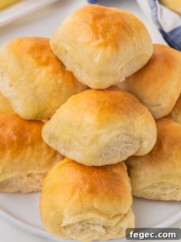 A stack of dinner rolls on a plate.