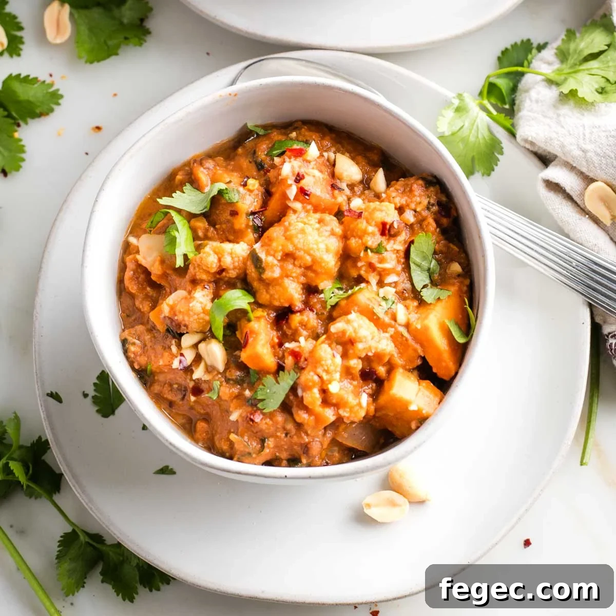 Bowl of chunky vegetable stew, garnished with fresh herbs and crushed peanuts.