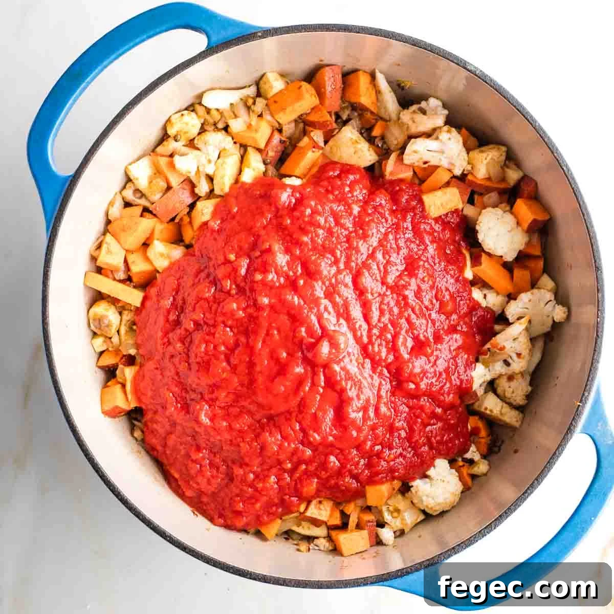 Crushed tomatoes on top of sauteed veggies in a dutch oven.