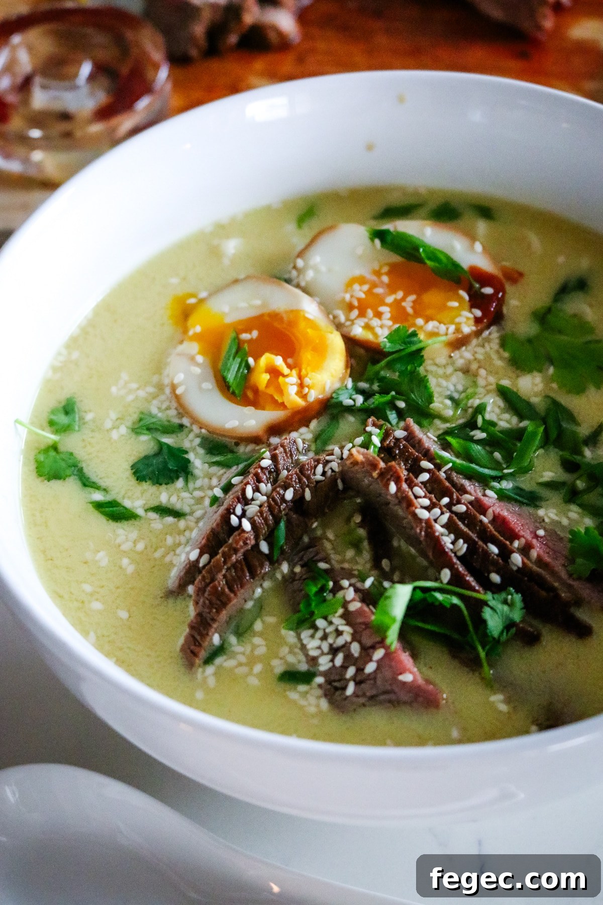 ramen with steak, noodles, and soft-boiled egg with green onions.