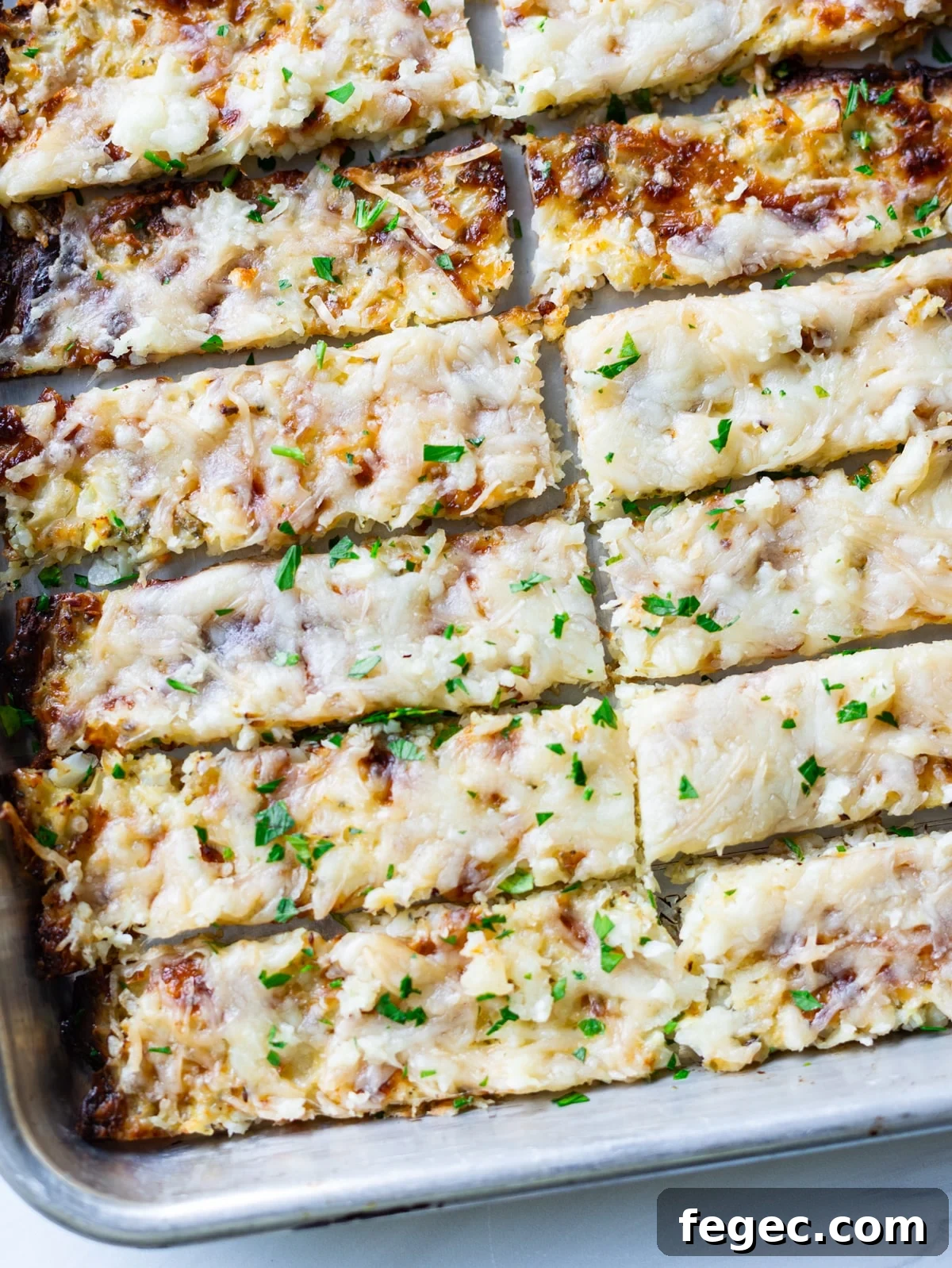 Cheesy Garlic Cauliflower Breadsticks Recipe for Low-Carb Snacking 2 Sliced cauliflower breadsticks on a baking tray.