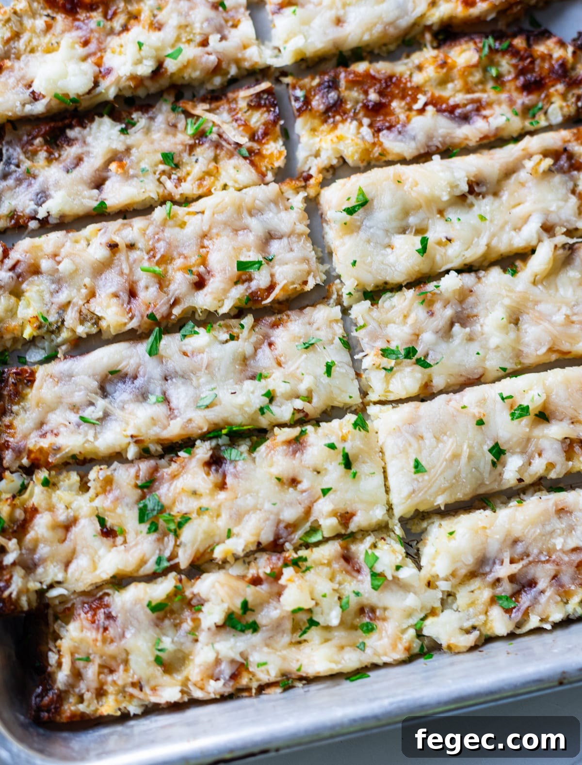 Cheesy Garlic Cauliflower Breadsticks Recipe for Low-Carb Snacking 11 Cauliflower breadsticks sliced on a baking sheet.