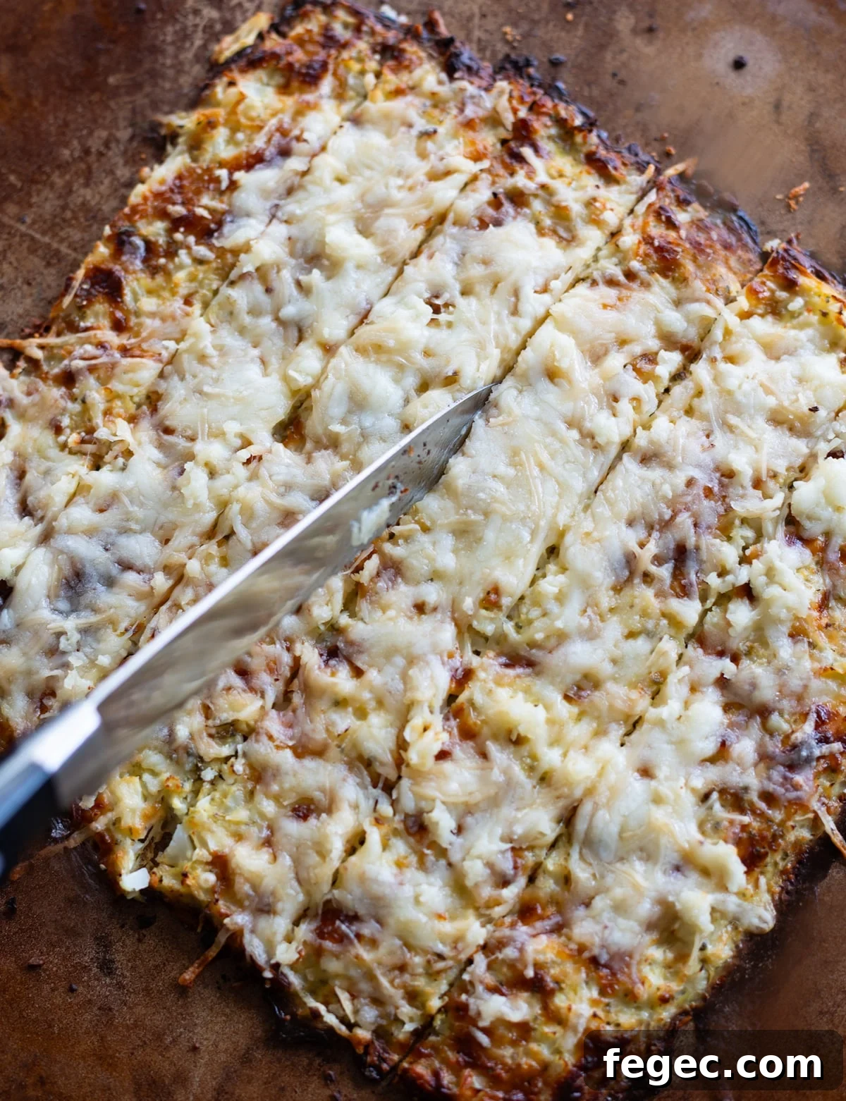 Cheesy Garlic Cauliflower Breadsticks Recipe for Low-Carb Snacking 10 Person slicing cauliflower breadsticks in preparation to serve.