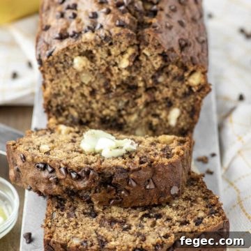 Whole wheat banana bread sliced with butter on serving platter.