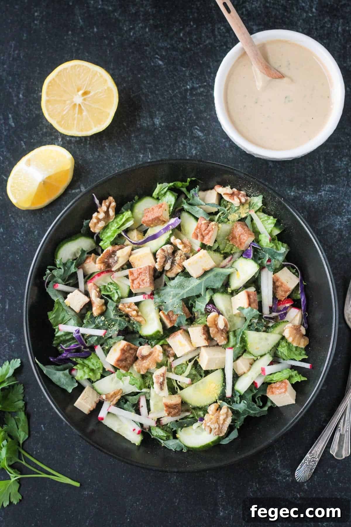 Salad with greens, vegetables, tofu, and walnuts in a black bowl.