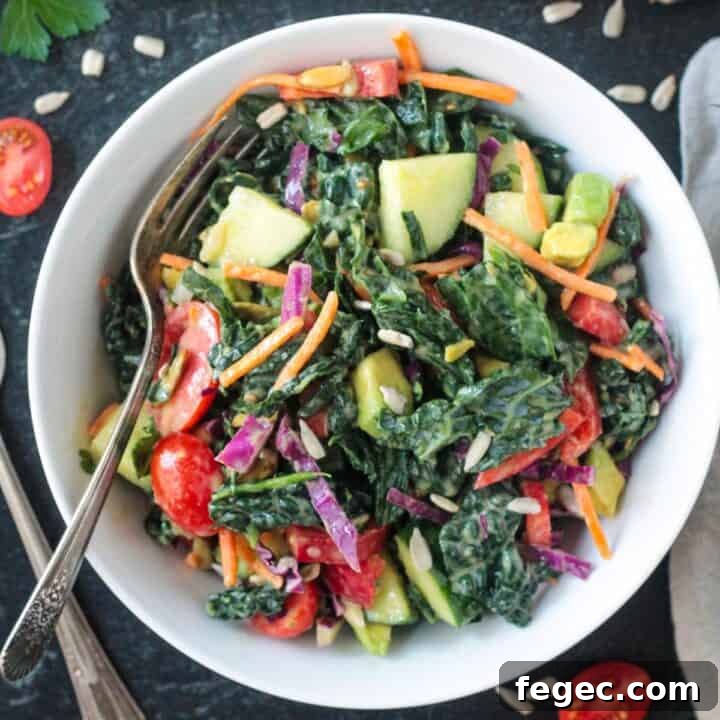 Chopped kale salad with a variety of vegetables in a white bowl.