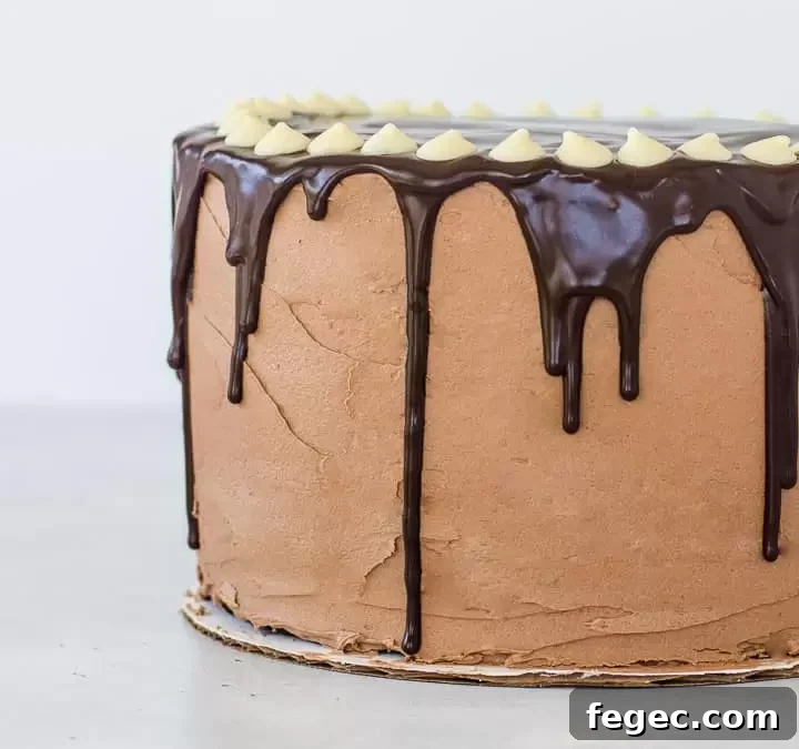 tuxedo cake on a cardboard circle with chocolate ganache dripping down the sides