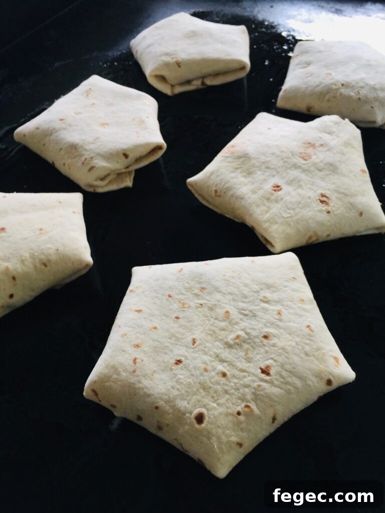 cooking Blackstone Fritos Crunchwraps on griddle before flipping