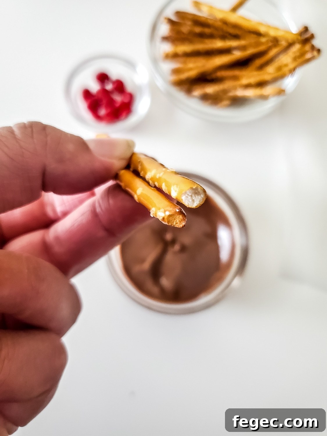Christmas Reindeer Pretzel Recipe with Photos 3 pretzel rods being dipped in chocolate