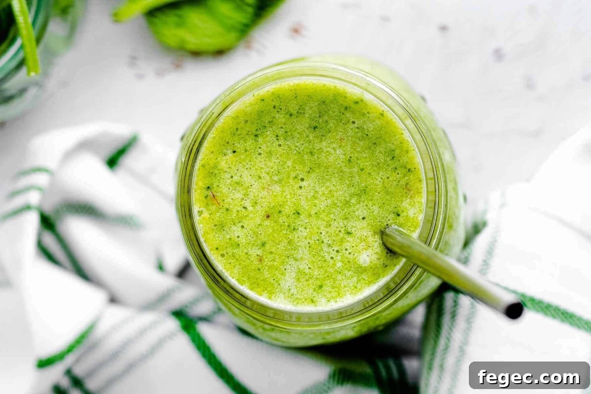 Island Green Tropical Smoothie Recipe for Refreshing Energy 3 overhead view of an island green tropical smoothie in a mason jar with a metal straw.