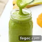 Island Green Tropical Smoothie Recipe for Refreshing Energy 6 pouring an island green tropical smoothie from a blender into a glass mason jar.