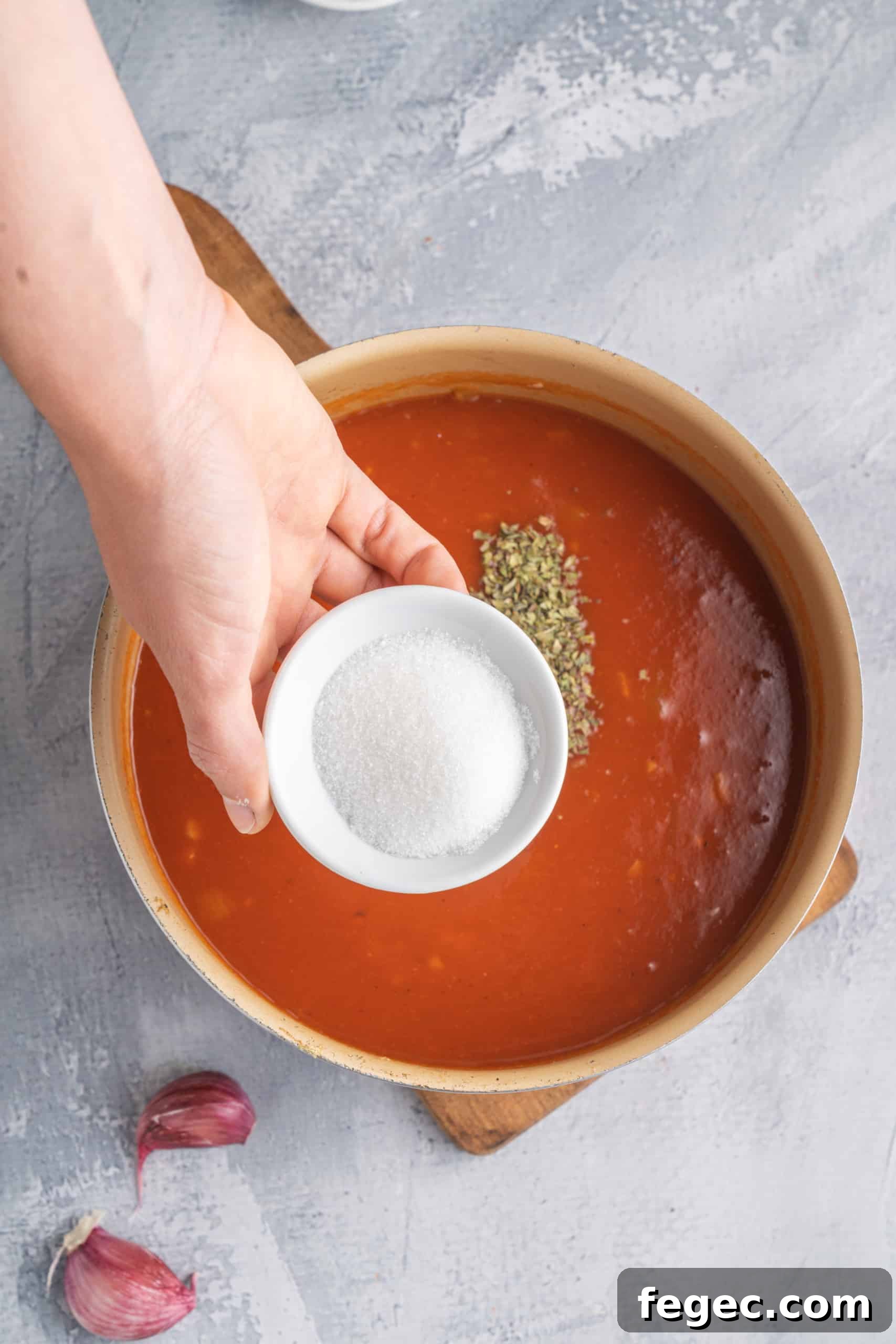 Adding salt to a saucepan of homemade tomato sauce.