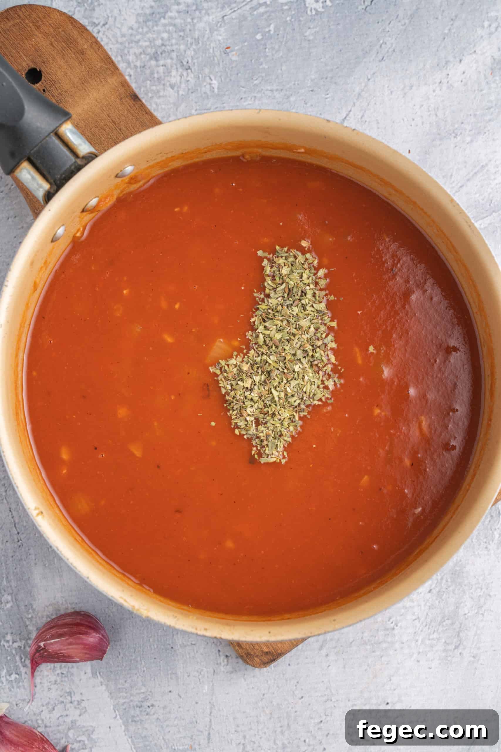 Dried herbs on top of gluten-free tomato sauce in a saucepan.