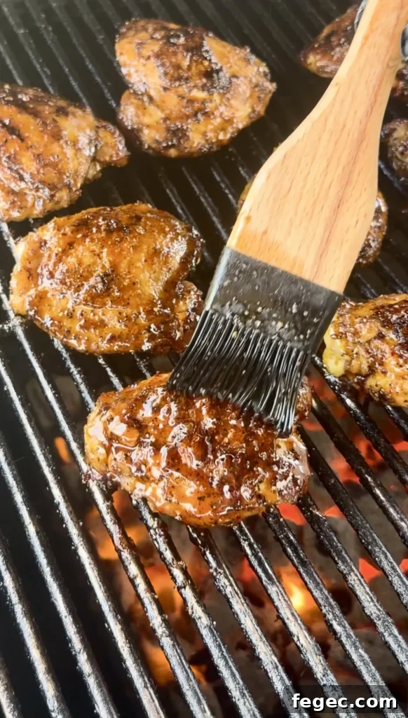 Juicy Grilled Chicken Thighs with Crispy Skin and Garlic Herb Rub 4 Honey chili crisp chicken thighs grilling on grates with wooden basting brush applying glaze over flames
