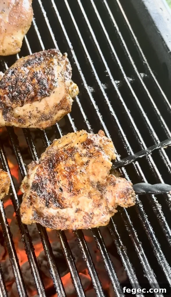Juicy Grilled Chicken Thighs with Crispy Skin and Garlic Herb Rub 8 Golden brown honey chili crisp chicken thighs with crispy seasoned skin cooking on black grill grates over flames