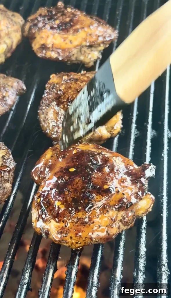 Juicy Grilled Chicken Thighs with Crispy Skin and Garlic Herb Rub 9 Honey chili crisp chicken thighs with caramelized glaze cooking on grill grates over flames