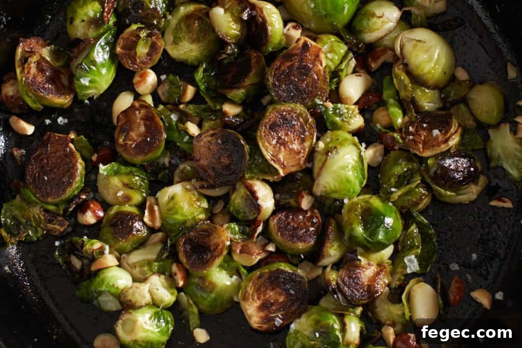 Pan fried brussels sprouts in a cast iron skillet with hazelnuts and garlic.