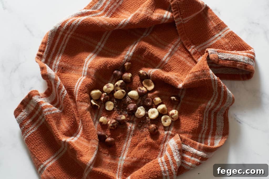 An orange kitchen towel with hazelnuts and their skins.
