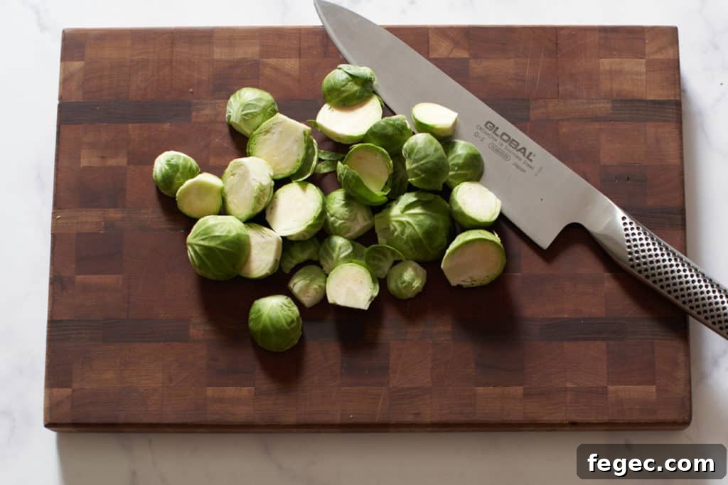 A knife on a cutting board with brussels sprouts.