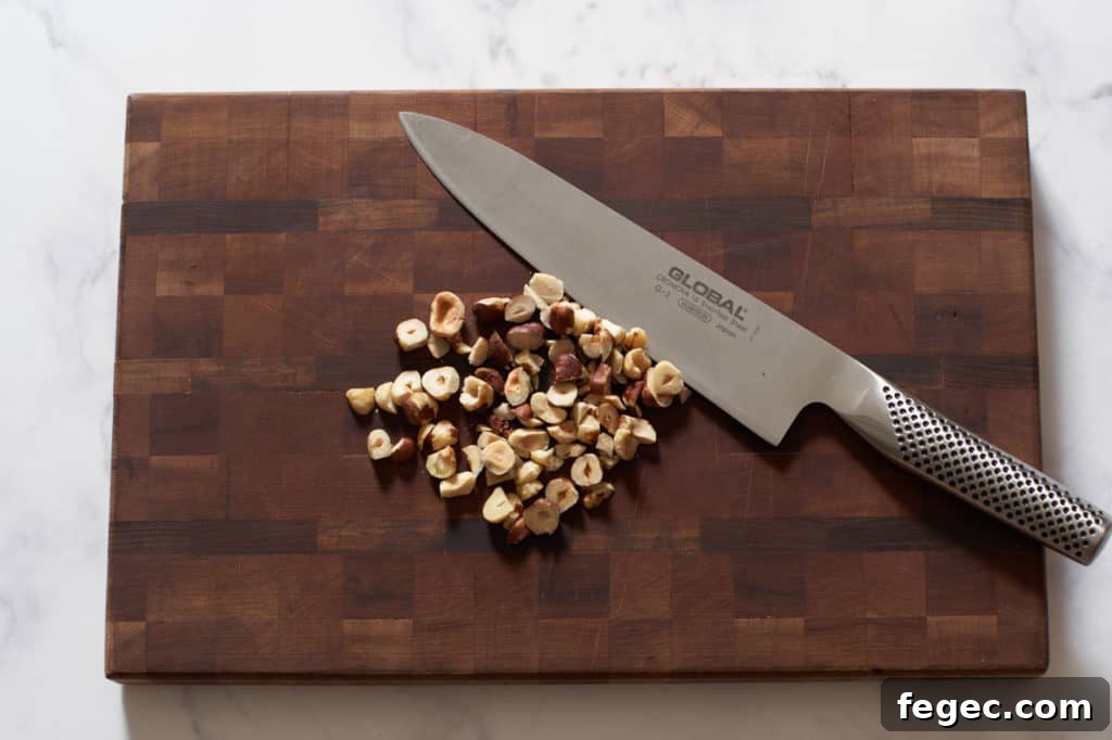 A knife on a cutting board with hazelnuts.