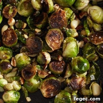 Crispy brussels sprouts in a cast iron skillet with hazelnuts and garlic.